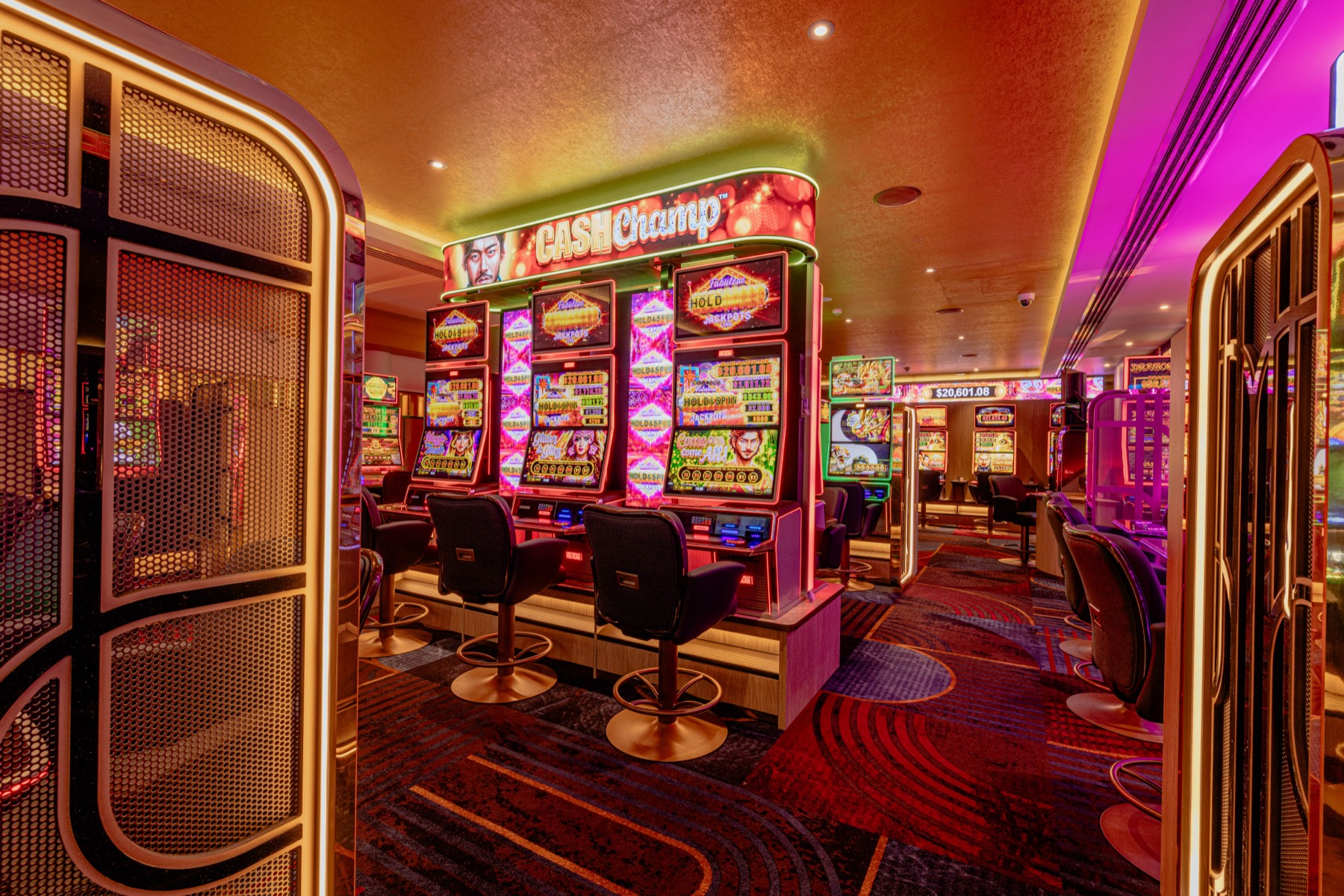 A bank of machines under a curved LED jackpot sign, seen through the mesh screens that divide the floor